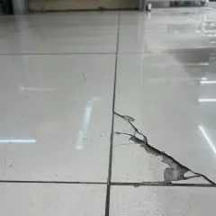 Detalle de una baldosa rota con grietas visibles. Aprende como reparar una baldosa rota sin cambiarla con este método.