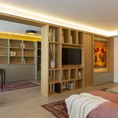 Estudio y salón con estanterías de madera, alfombras y varios tipos de luces que crean ambiente.