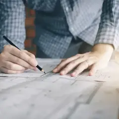 Manos de diseñador de interiores trabajando en planos. ¿Cuánto te pagan por ser diseñadora de interiores?