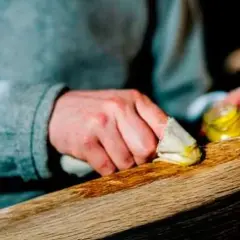 Manos aplicando cera a un trozo de madera. El proceso de **decapar madera** revela su belleza natural.