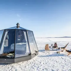 Modernas casas de cristal en el Polo Norte, con camas acogedoras y sillas al aire libre para disfrutar del paisaje nevado.