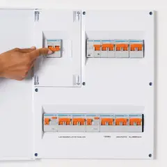 Panel de circuitos vivienda con interruptores naranjas. Una mano activa uno de los interruptores.