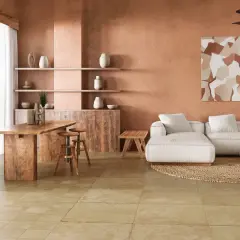 Amplio salón con paredes terracota, sofá blanco, mesa de madera y un cálido suelo terracota interior.
