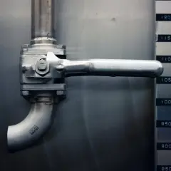 Grifo de acero inoxidable en una red horizontal de saneamiento, junto a un medidor de nivel.
