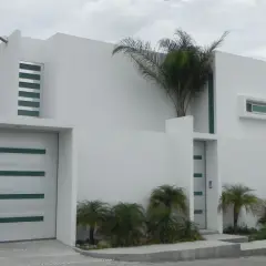 Casa moderna con líneas limpias y un estilo arquitectónico minimalista. Puerta de garaje blanca con detalles verdes.