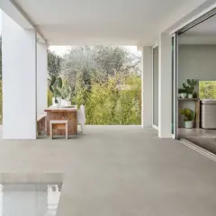 Terraza moderna con mesa de madera y cactus, sobre un impecable suelo gres que se extiende hasta una piscina.