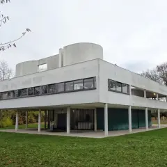 Casa de cristal y acero, un ícono del movimiento moderno arquitectura, con líneas limpias y grandes ventanales sobre pilotes.