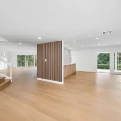 Espacio moderno con puerta blanca, escaleras, pared divisoria de madera y suelo laminado de roble claro.