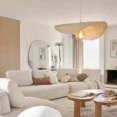 Sofá blanco acogedor, mesas de madera orgánicas y un espejo ovalado grande. Un ejemplo de decoraciones de interiores modernas y minimalistas.