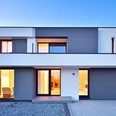 Moderna casa con amplios ventanales y puerta de garaje gris. Un ejemplo de construcción de viviendas contemporáneas.