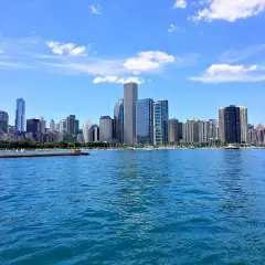 Impresionante vista de los chicago rascacielos reflejados en el agua azul, bajo un cielo despejado con nubes blancas.