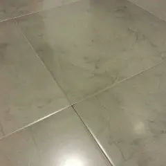 Detalle de azulejos rectificados con juntas finas, mostrando posibles problemas de suciedad o desgaste en las uniones.