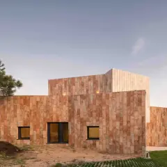 Edificio moderno con paredes porcelanico para fachadas exteriores, rodeado de vegetación y bajo un cielo despejado.