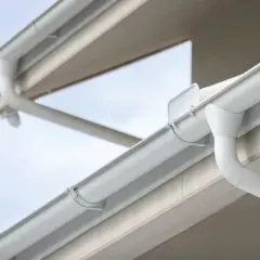 Sistema de canalones blancos en un edificio. La imagen muestra cómo se conectan las bajantes para evacuar el agua.