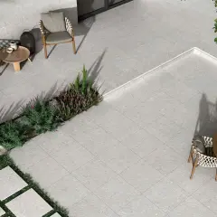 Terraza moderna con mobiliario de exterior y vegetación. El suelo está cubierto por un elegante **azulejo rectificado** de tonos grises, creando un espacio acogedor.