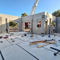 Construcción de casa con paneles prefabricados. Se ve el suelo de hormigón, paredes levantadas y herramientas. ¿Cuánto cuesta terminar una casa en obra?