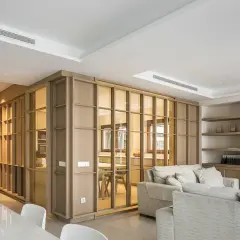 Un espacio moderno y luminoso, ideal para diseñar interiores. Muebles de madera y cristal separan ambientes, creando un hogar acogedor.