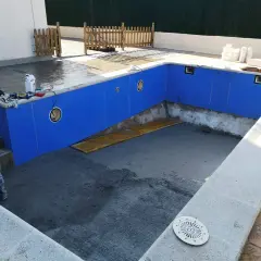 Piscina en construcción, paredes azules listas para recibir el gresite. Herramientas y materiales a un lado.