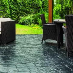 Terrazas con suelo de piedra oscura, muebles de mimbre y vegetación exuberante.
