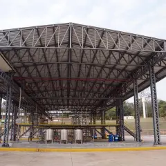 Estructura metálica de gran tamaño con cubiertas estructurales que albergan equipos industriales y tuberías.