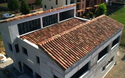 Edificio en construcción con tejado de tejas rojas, una cubierta plana o inclinada que protege la estructura.