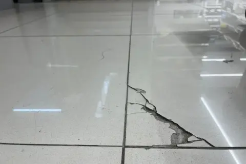 Detalle de una baldosa rota con grietas visibles. Aprende como reparar una baldosa rota sin cambiarla con este método.