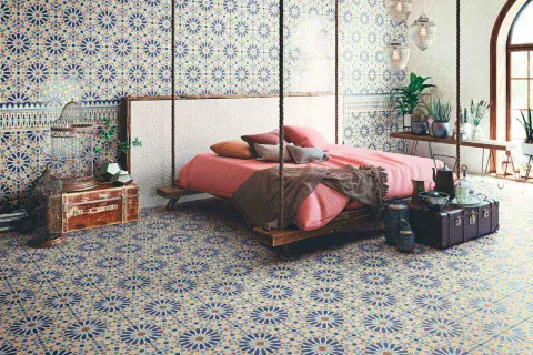 Dormitorio con suelo y paredes cubiertos de **azulejos Alhambra** de diseño geométrico. Cama suspendida y decoración exótica.