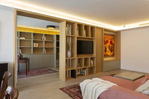 Estudio y salón con estanterías de madera, alfombras y varios tipos de luces que crean ambiente.