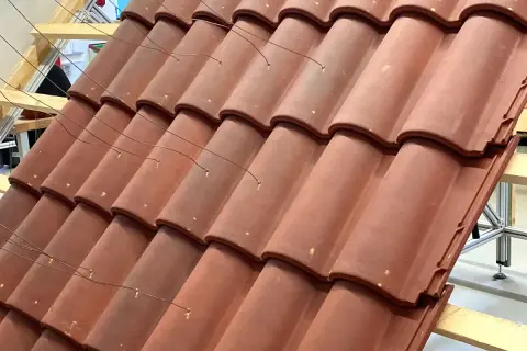 Detalle de la colocación teja árabe, con alambres finos sujetando las piezas sobre una estructura de madera.