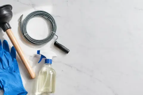 Desatascador, guantes, limpiador y serpentina para solucionar un atasco de tubería.