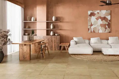 Amplio salón con paredes terracota, sofá blanco, mesa de madera y un cálido suelo terracota interior.