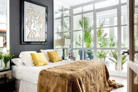 Ideas para diseñar tu habitacion: cama con manta peluda, cuadros abstractos y mucha luz natural.