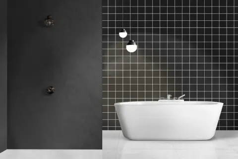 Modern bathroom with a freestanding white tub and a dark tiled wall. Ideal for **revestimiento paredes baño sin obras**.