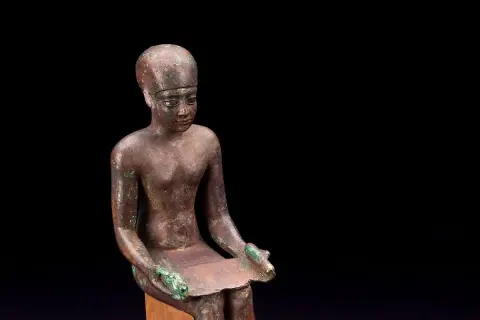 Estatua de bronce de Imhotep, el primer arquitecto de la historia, sentado con un papiro.