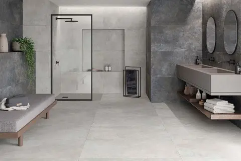 Baño moderno con ducha, lavabo doble y banco. La diferencia entre baldosa y azulejo se aprecia en los acabados de pared y suelo.