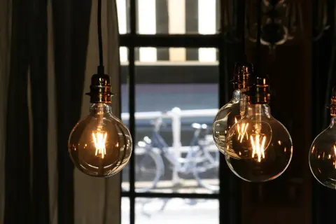 Lámparas Edison con filamentos visibles, creando una atmósfera cálida. La luz tenue sugiere pocos lúmenes por m2, ideal para un ambiente acogedor.