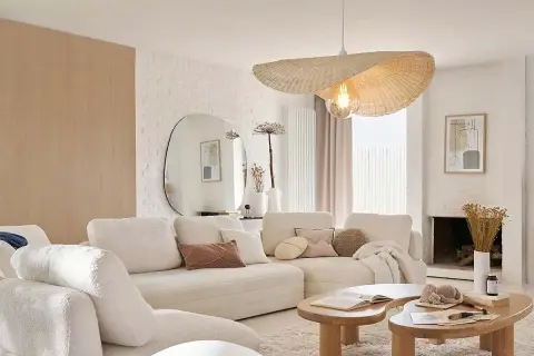 Sofá blanco acogedor, mesas de madera orgánicas y un espejo ovalado grande. Un ejemplo de decoraciones de interiores modernas y minimalistas.