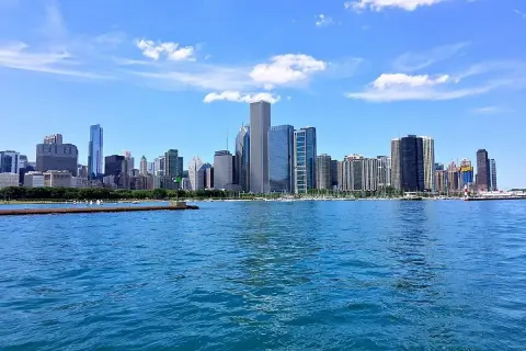 Impresionante vista de los chicago rascacielos reflejados en el agua azul, bajo un cielo despejado con nubes blancas.