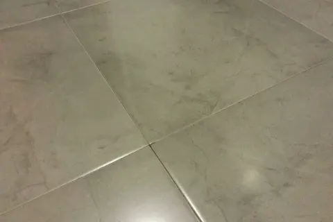 Detalle de azulejos rectificados con juntas finas, mostrando posibles problemas de suciedad o desgaste en las uniones.
