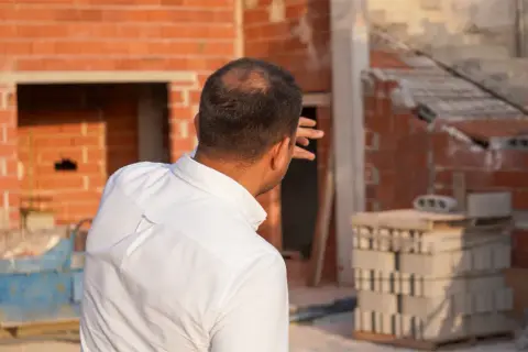 Un arquitecto supervisa la construcción de una casa, evaluando cuánto vale un arquitecto para construir una casa.