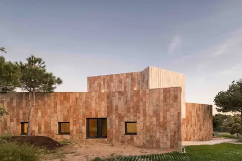 Edificio moderno con paredes porcelanico para fachadas exteriores, rodeado de vegetación y bajo un cielo despejado.