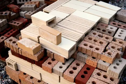 Montón de ladrillos de construcción tradicional, apilados en diferentes tamaños y colores, listos para crear estructuras sólidas.