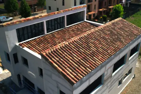 Edificio en construcción con tejado de tejas rojas, una cubierta plana o inclinada que protege la estructura.