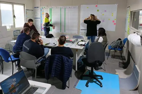 Equipo discutiendo un plan de proyecto en una sala de reuniones, aplicando principios de **lean construction** para optimizar el proceso.