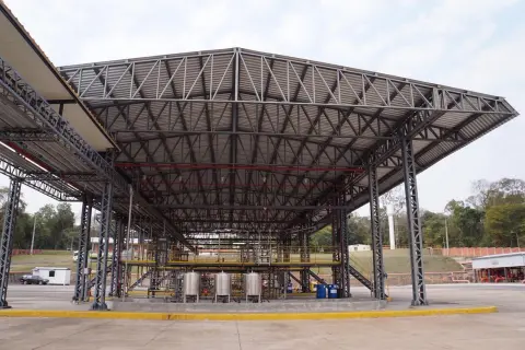 Estructura metálica de gran tamaño con cubiertas estructurales que albergan equipos industriales y tuberías.