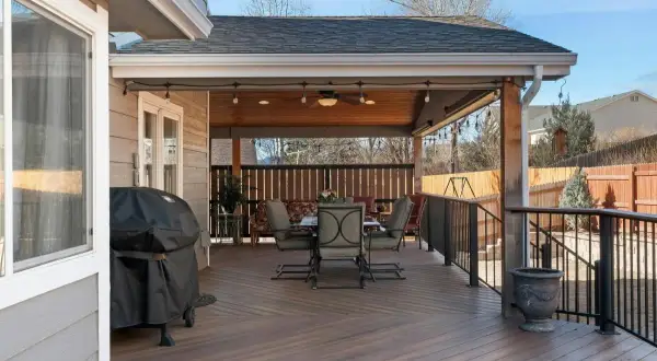 Terraza con mesa y sillas bajo un techo de tipos de cubiertas inclinadas. Parrilla cubierta a la izquierda.