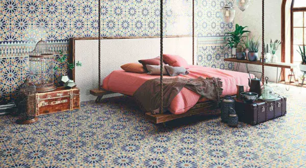 Dormitorio con suelo y paredes cubiertos de **azulejos Alhambra** de diseño geométrico. Cama suspendida y decoración exótica.