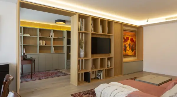 Estudio y salón con estanterías de madera, alfombras y varios tipos de luces que crean ambiente.