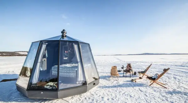 Modernas casas de cristal en el Polo Norte, con camas acogedoras y sillas al aire libre para disfrutar del paisaje nevado.