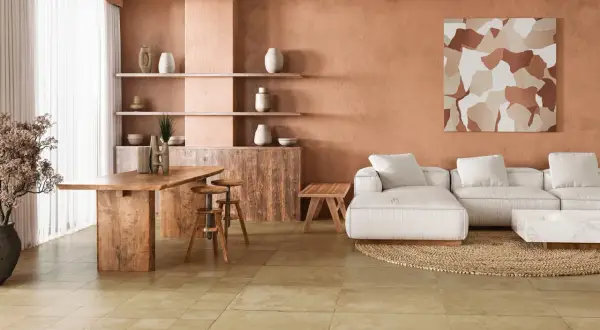 Amplio salón con paredes terracota, sofá blanco, mesa de madera y un cálido suelo terracota interior.